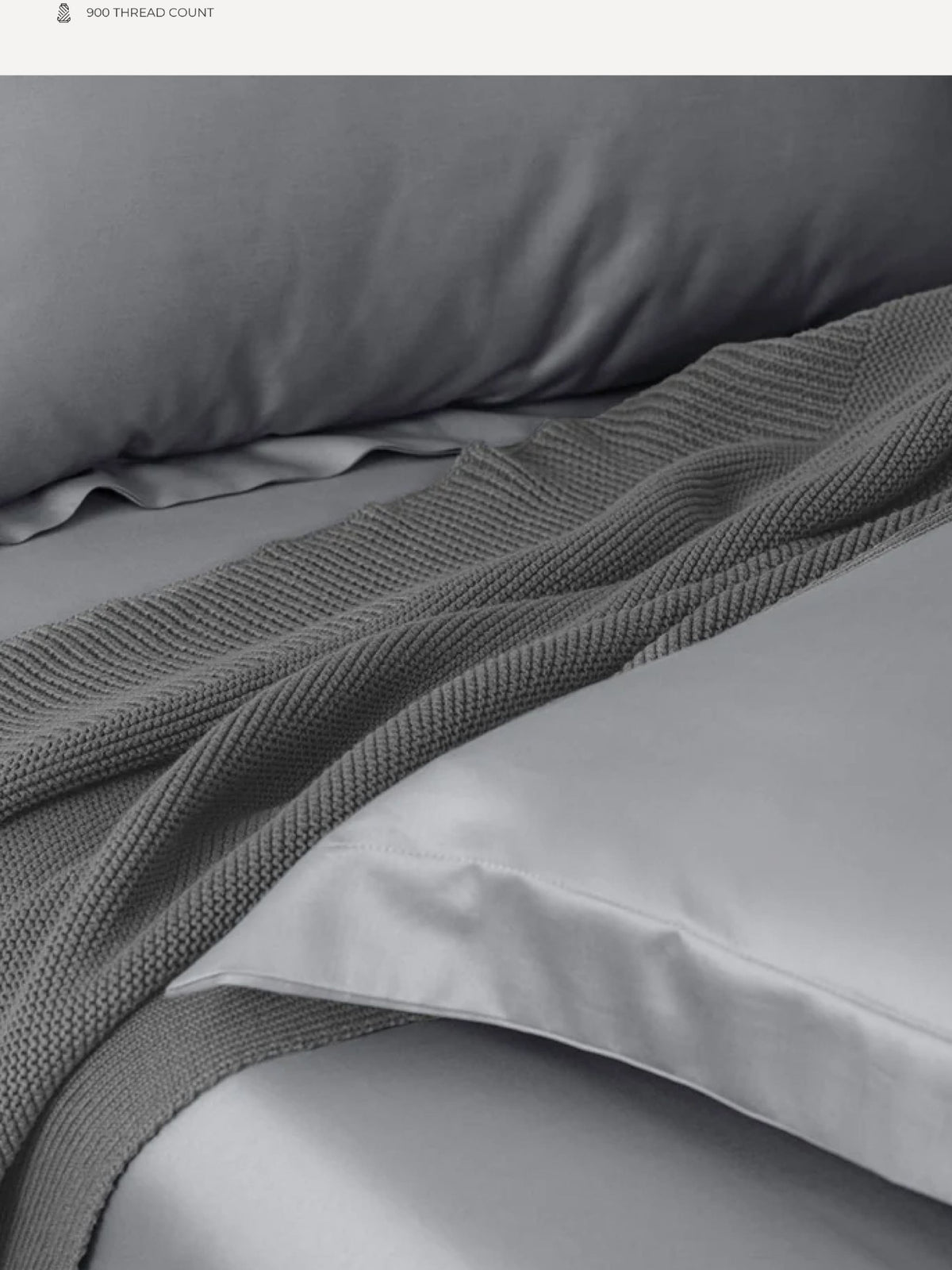 Grey Supima cotton bedding with a knitted throw folded across it