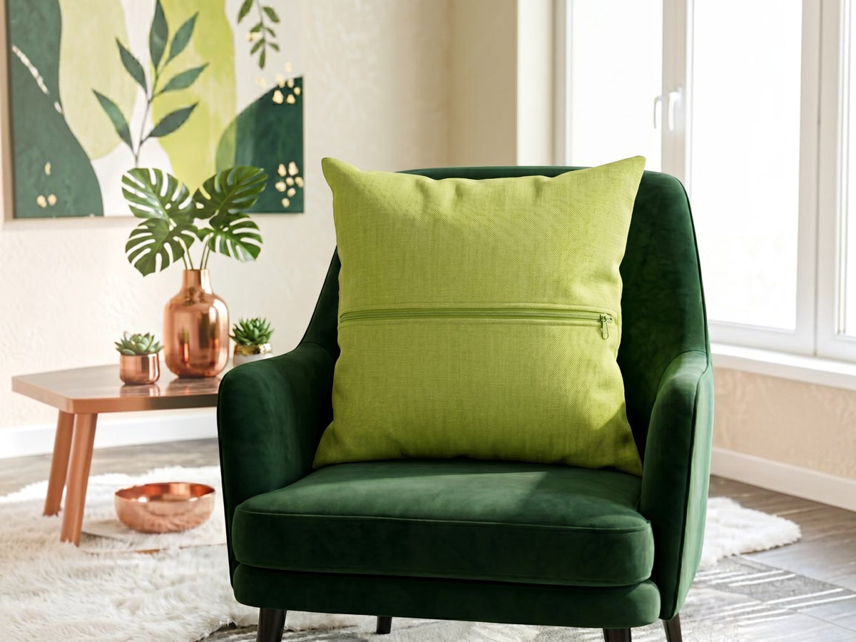Green plain cotton cushion cover with subtle woven texture displayed on a dark green accent chair