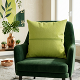Green plain cotton cushion cover with subtle woven texture displayed on a dark green accent chair