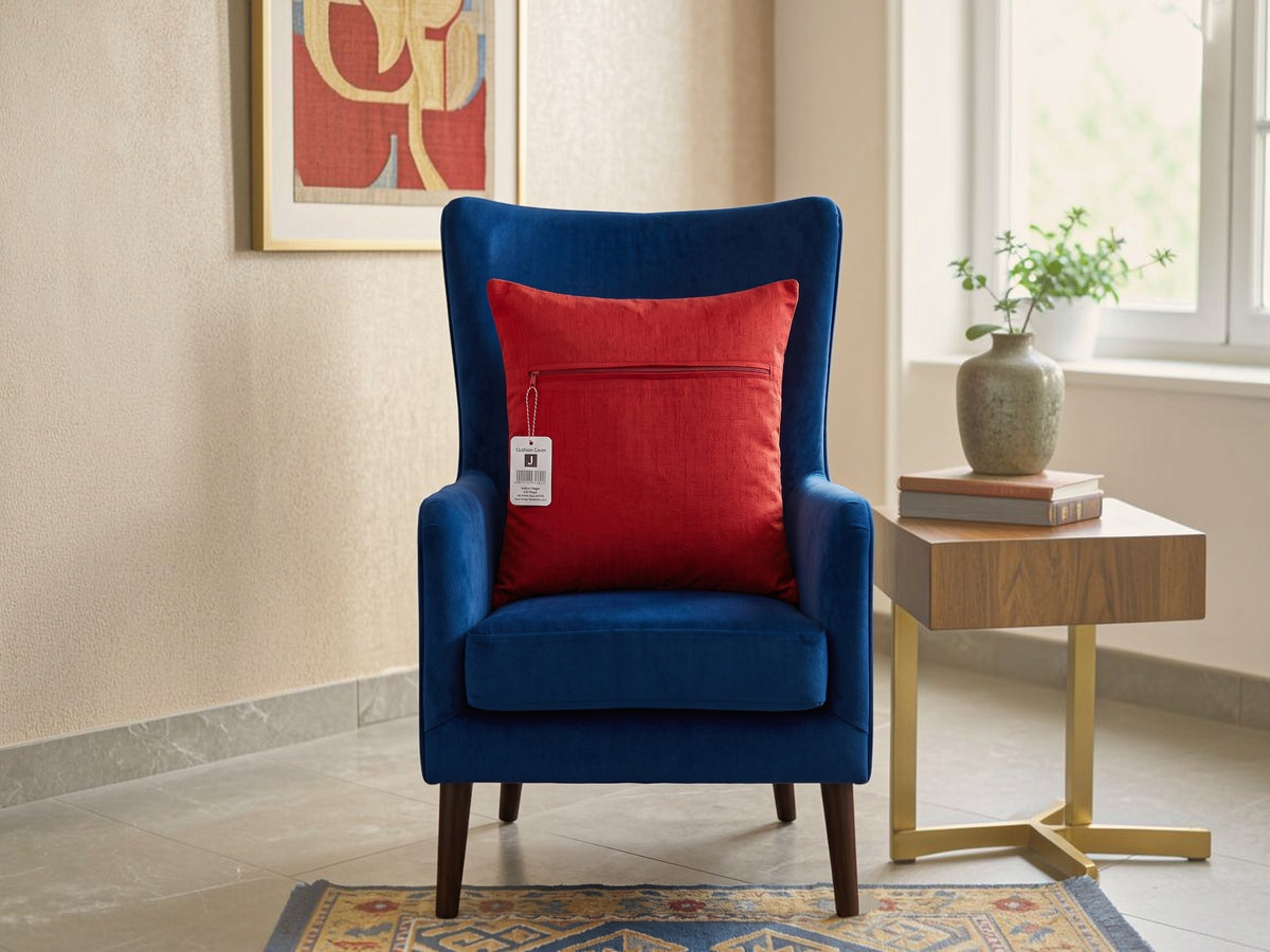 Red embroidered polysilk cushion cover with golden ornamental border design on a blue accent chair