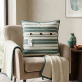 Green and white striped cotton cushion cover with contrast piping displayed on a beige accent chair