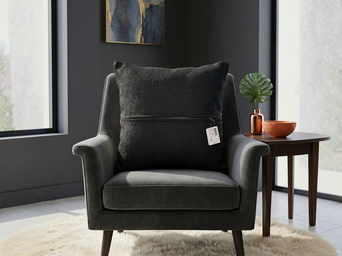Black textured woven cushion cover with beige geometric detailing placed on a modern armchair