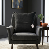 Black textured woven cushion cover with beige geometric detailing placed on a modern armchair