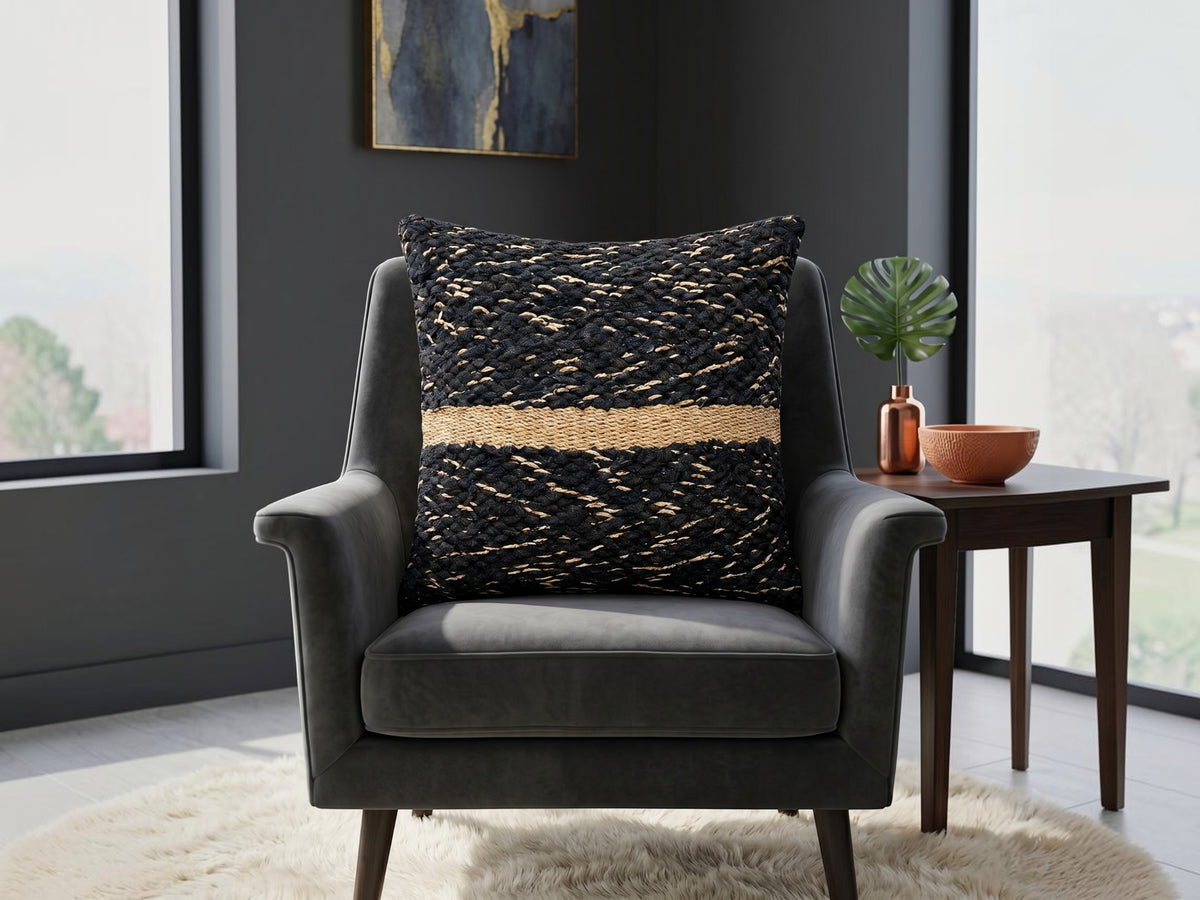 Black textured woven cushion cover with beige geometric detailing placed on a modern armchair