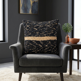 Black textured woven cushion cover with beige geometric detailing placed on a modern armchair