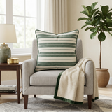 Green and white striped cotton cushion cover with contrast piping displayed on a beige accent chair