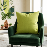 Green plain cotton cushion cover with subtle woven texture displayed on a dark green accent chair