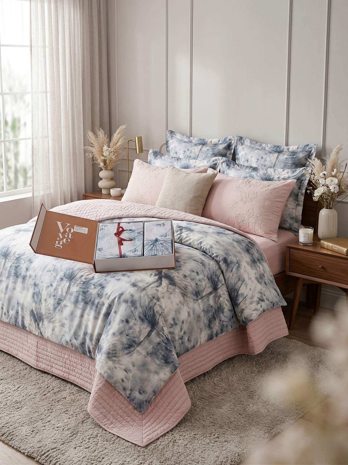 Bed dressed in a blue and white tie-dye bedsheet with a blush quilted border
