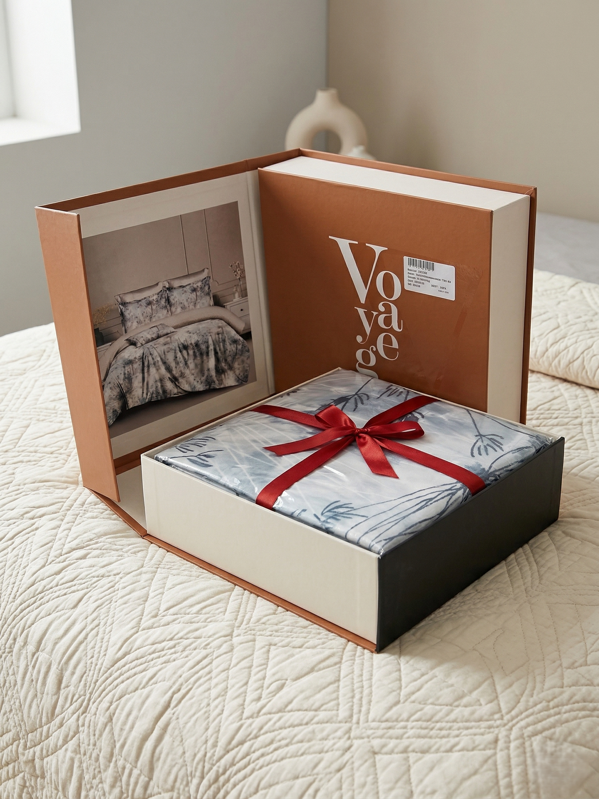 Open Voyage gift box with a red ribbon tied around the folded bedsheet