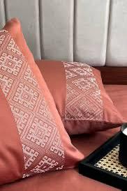 Close-up of terracotta pillow covers with a beige diamond-lattice embroidered band