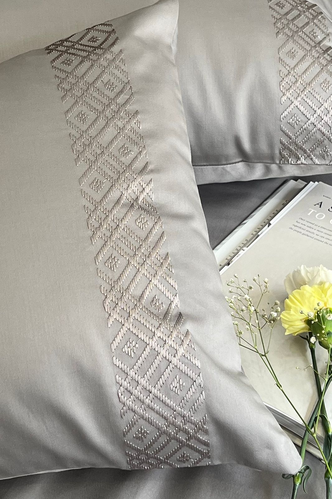 Close-up of the cream diamond embroidered band on a silver grey pillow cover