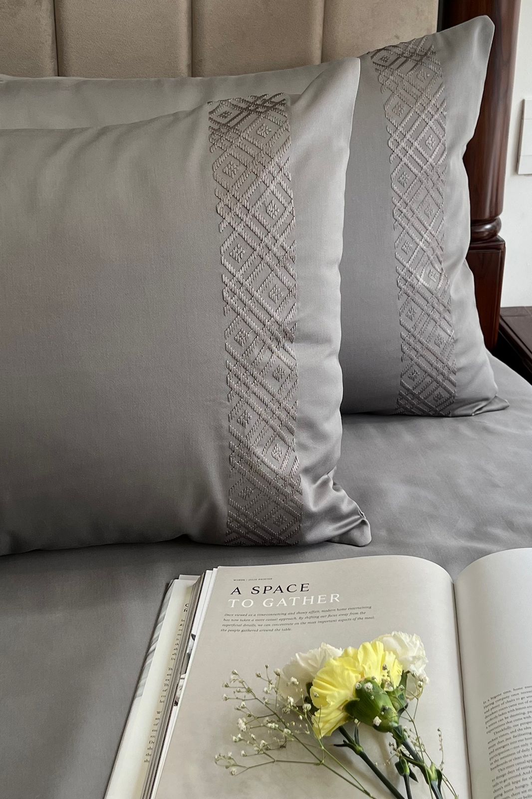 Silver grey bedding with diamond banded pillow covers and an open magazine