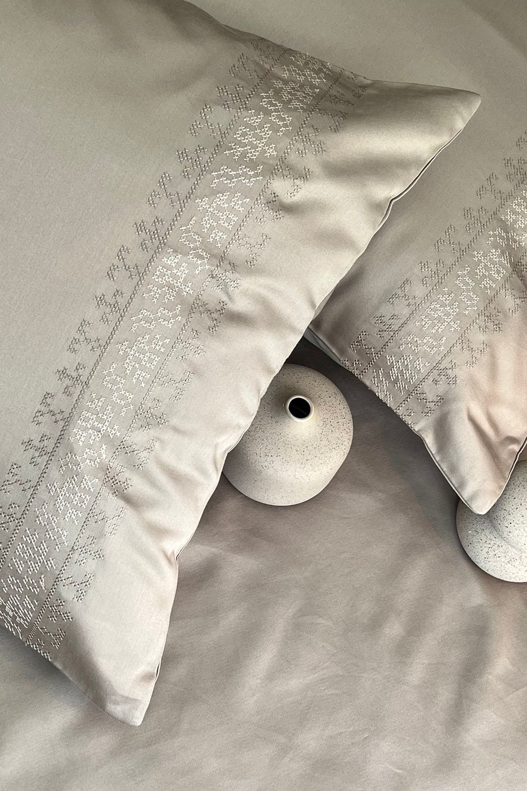 Greige embroidered-band pillows on a made bed, Greige Delight Collection