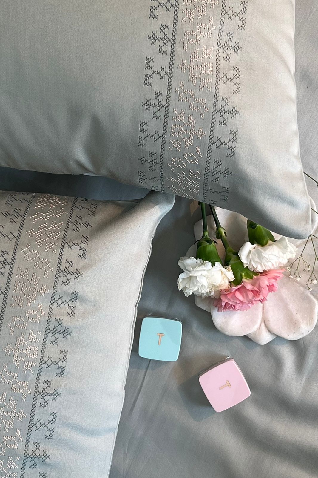 Sage green bedding with a grey and metallic cross-stitch embroidered band