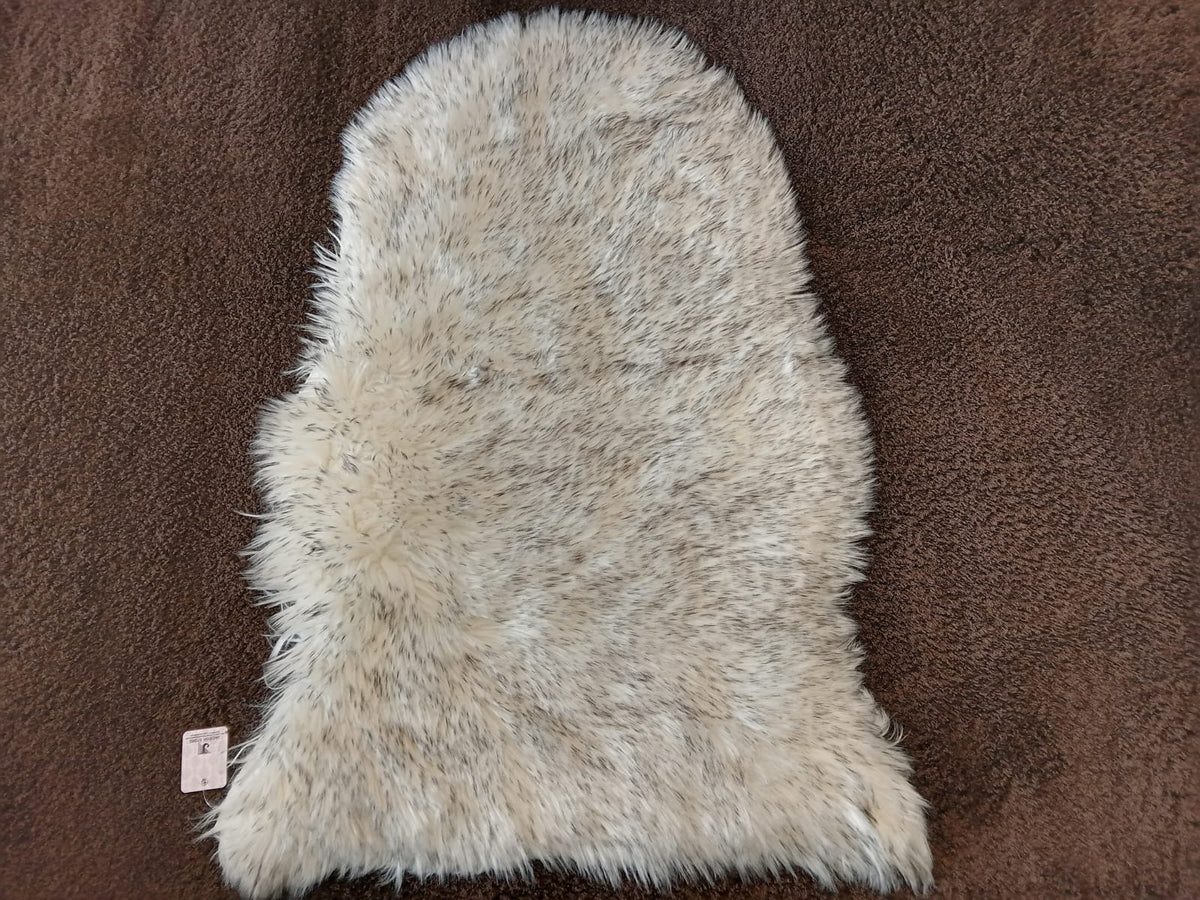 Grey-tipped cream faux sheepskin bedside runner laid on a brown carpet