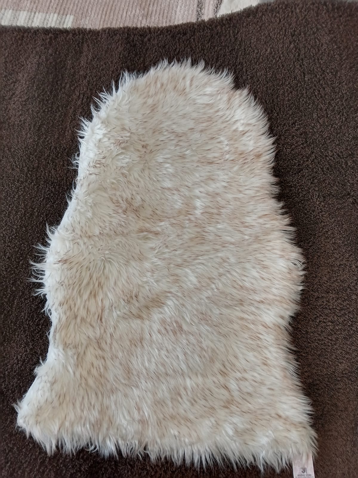 Ivory faux sheepskin bedside runner laid on a brown carpet