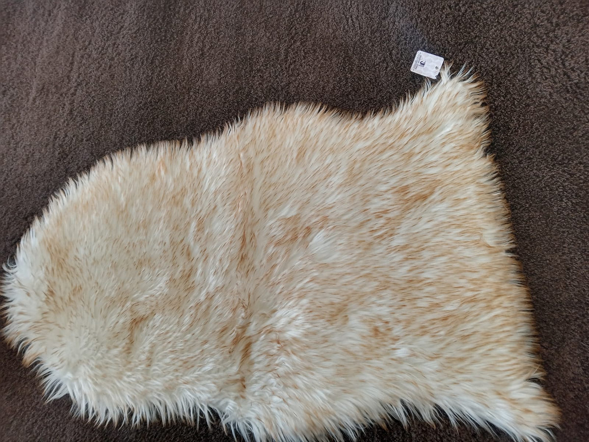 Close view of a blonde faux sheepskin bedside runner's long pile