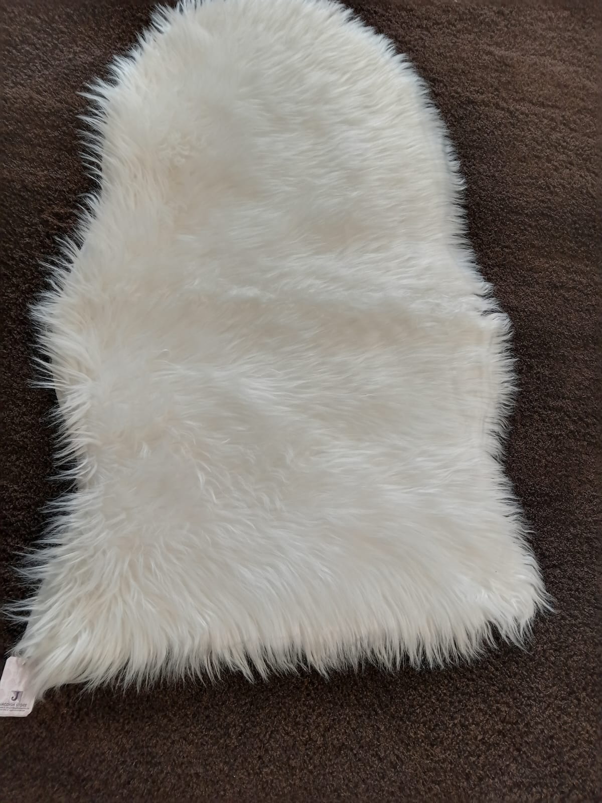 Pure white faux sheepskin bedside runner laid on a brown carpet