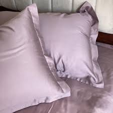 Mauve-grey satin pillow covers styled on a bed, close-up view