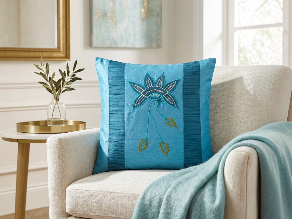 Jagdish Store embroidered decorative cushion cover in shimmering turquoise with teal, white, and gold floral embroidery and teal striped panels.