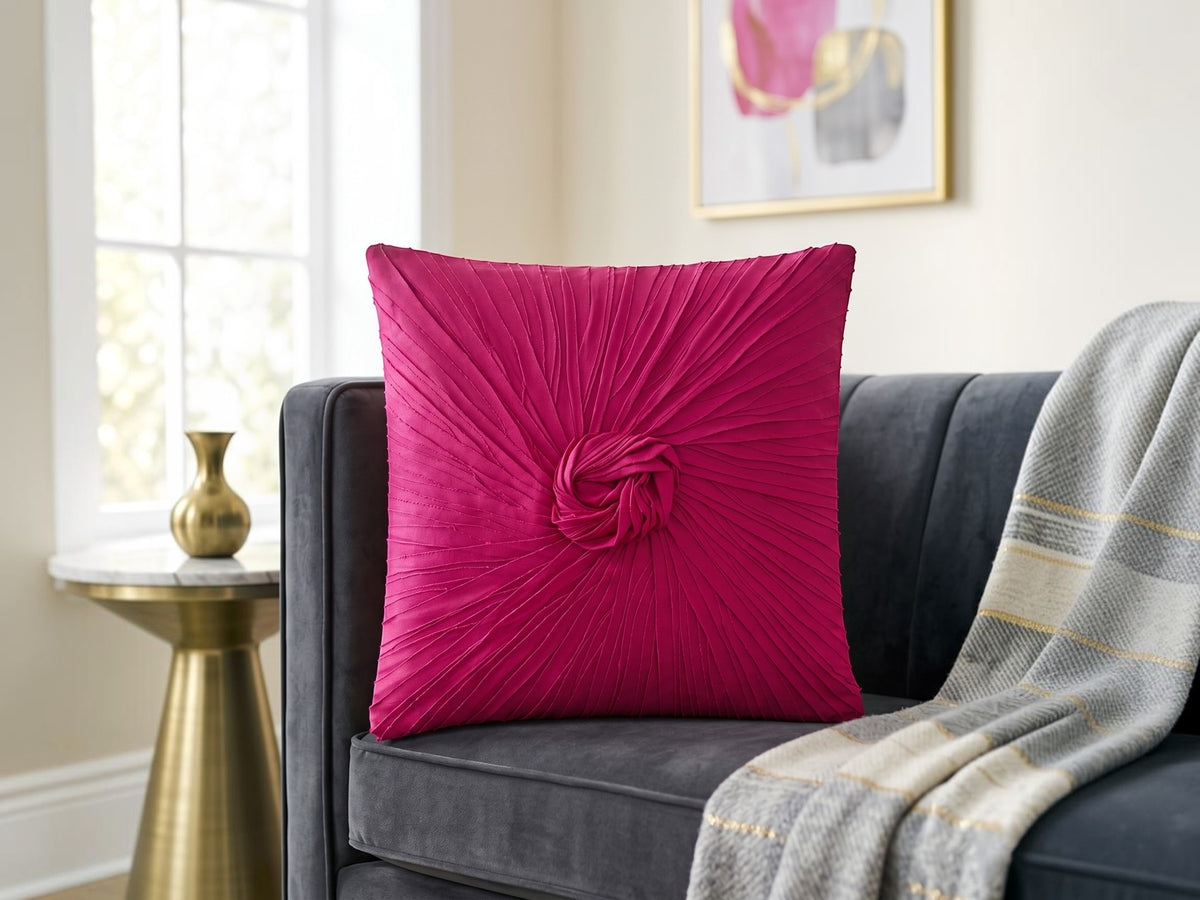Pink pleated pillow on a gray couch with a gold side table and abstract art in the background.