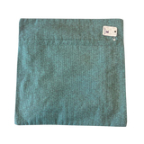 Jagdish Store teal woven throw pillow cover with a back zipper closure, displayed on a soft white faux fur surface.