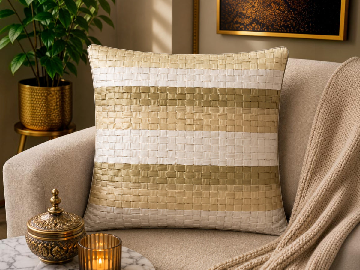 Jagdish Store decorative woven cushion cover in cream and gold with a subtle striped texture on a soft rug.