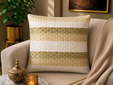 Jagdish Store decorative woven cushion cover in cream and gold with a subtle striped texture on a soft rug.
