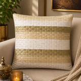 Jagdish Store decorative woven cushion cover in cream and gold with a subtle striped texture on a soft rug.