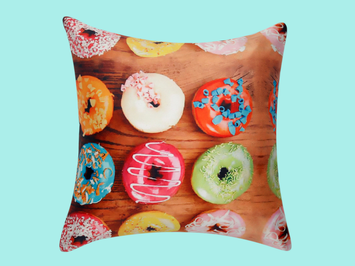 Cushion cover printed with iced doughnuts in bright colours on a wooden background
