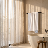 White cotton bath towel with woven border hanging on a bathroom towel bar