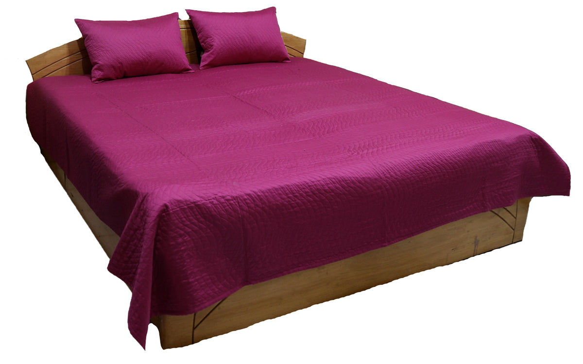 Magenta side of the reversible quilted bedcover with two pillow covers, angled view