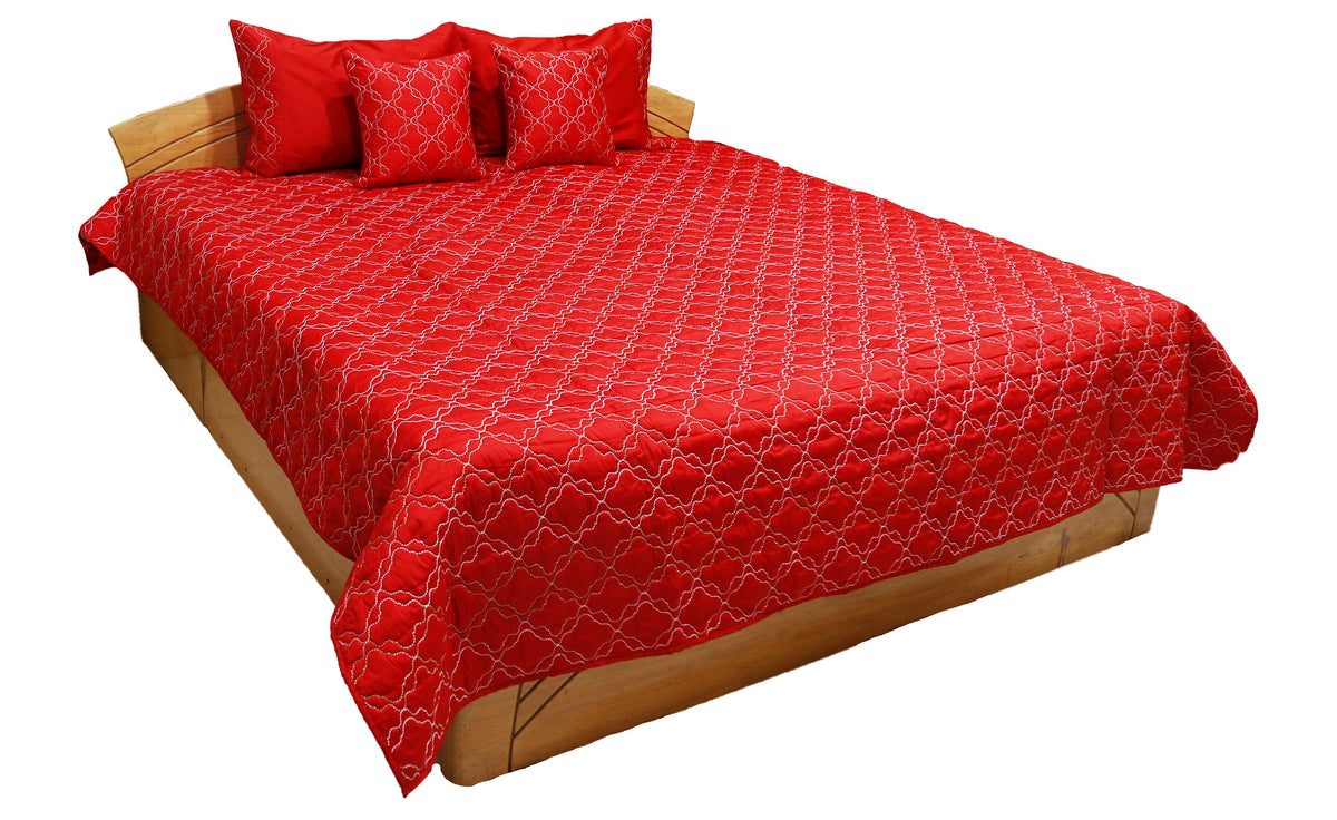 Red quilted double bedcover with a white diamond-lattice embroidery, styled with matching pillow and cushion covers on a wooden bed frame