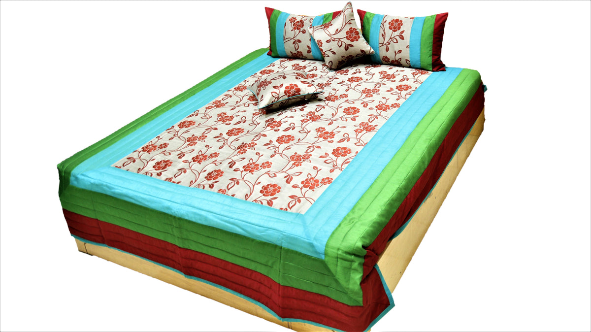 Green, red and blue bordered quilted bedcover set with a floral centre panel on a bed