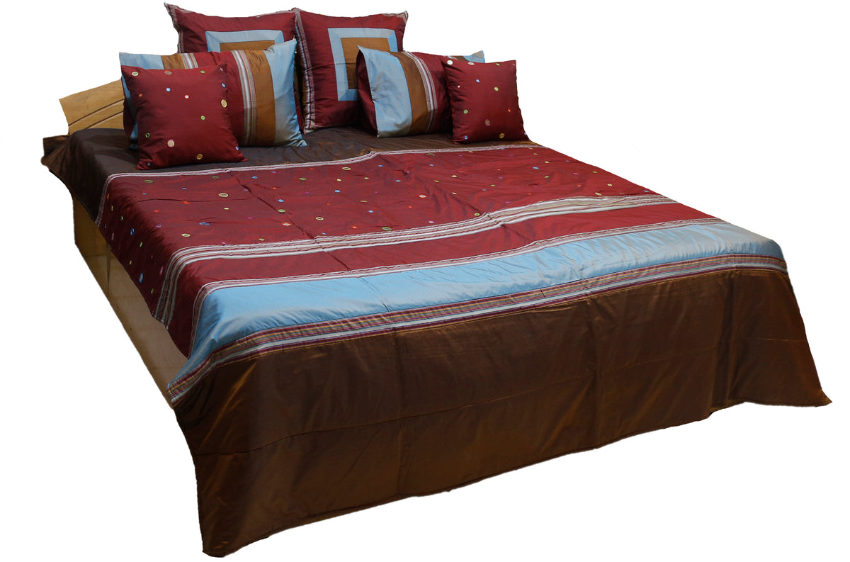 Maroon bedcover with brown and blue bands, mirror work dots and six cushions