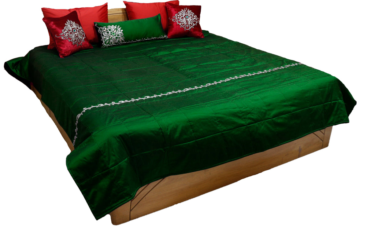 Bottle green silk bedcover with silver pearl work band and red cushions, angled view