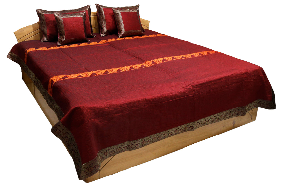 Maroon-red satin double bedcover with a grey-brown zari-brocade border, styled with matching pillow and cushion covers