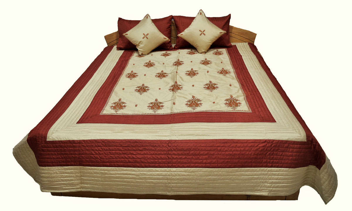 Maroon and cream double bedcover with a floral-embroidered border, angled view on the bed