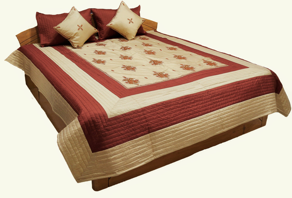 Maroon and cream double bedcover with a floral-embroidered border, styled with matching diamond-motif pillow covers