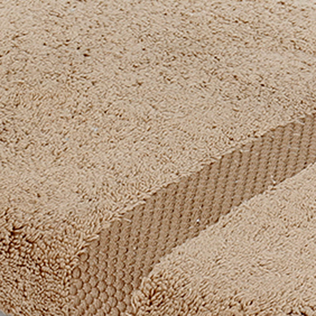 Close-up of sand-beige cotton bath towel folded, showing the honeycomb woven border texture