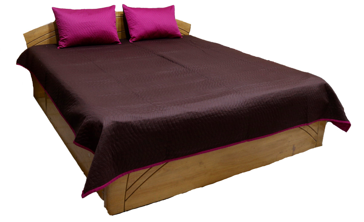 Aubergine quilted bedcover with magenta pillow covers and pink piped edge, angled view