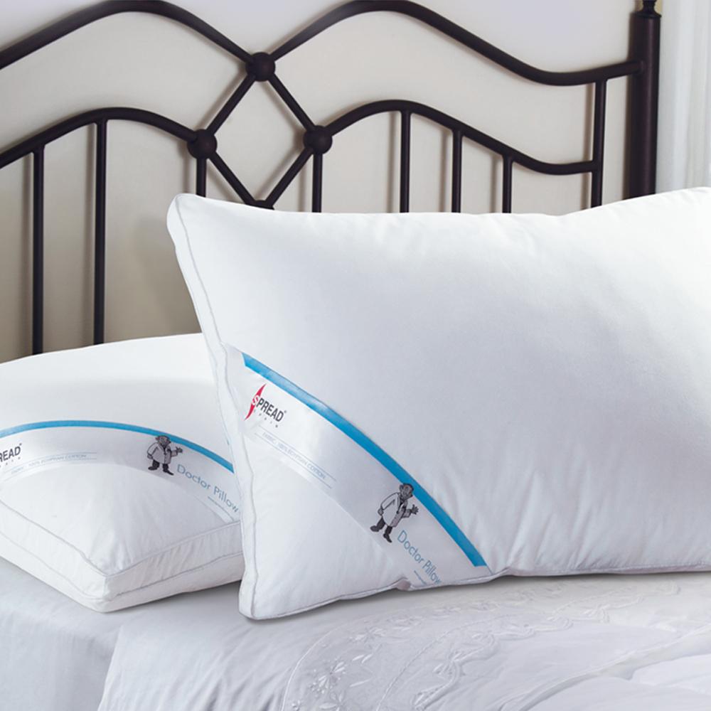 Two white Doctor Pillows with blue Spread branding on a metal framed bed