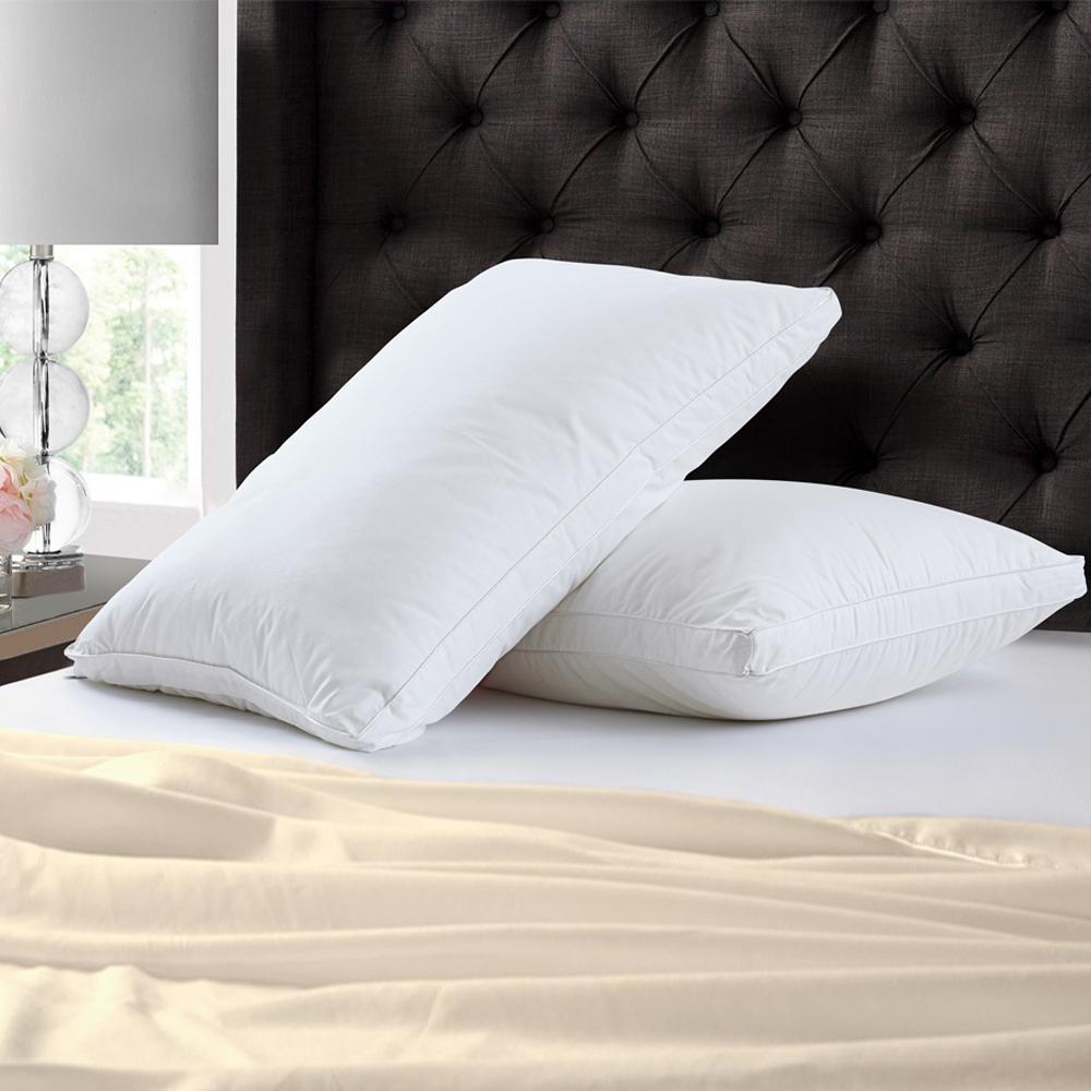 Two plain white piped pillows against a dark tufted headboard