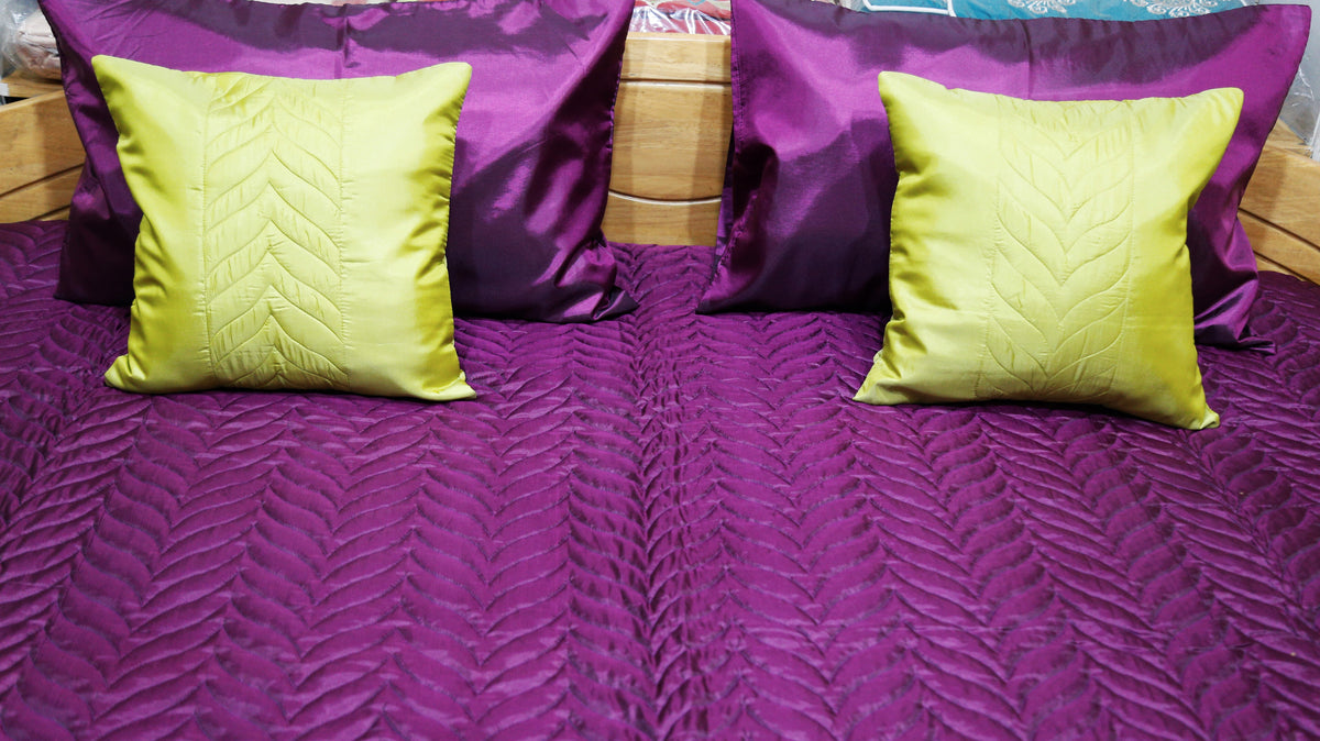 Close-up of the chartreuse-yellow embossed cushion covers against the purple bedcover