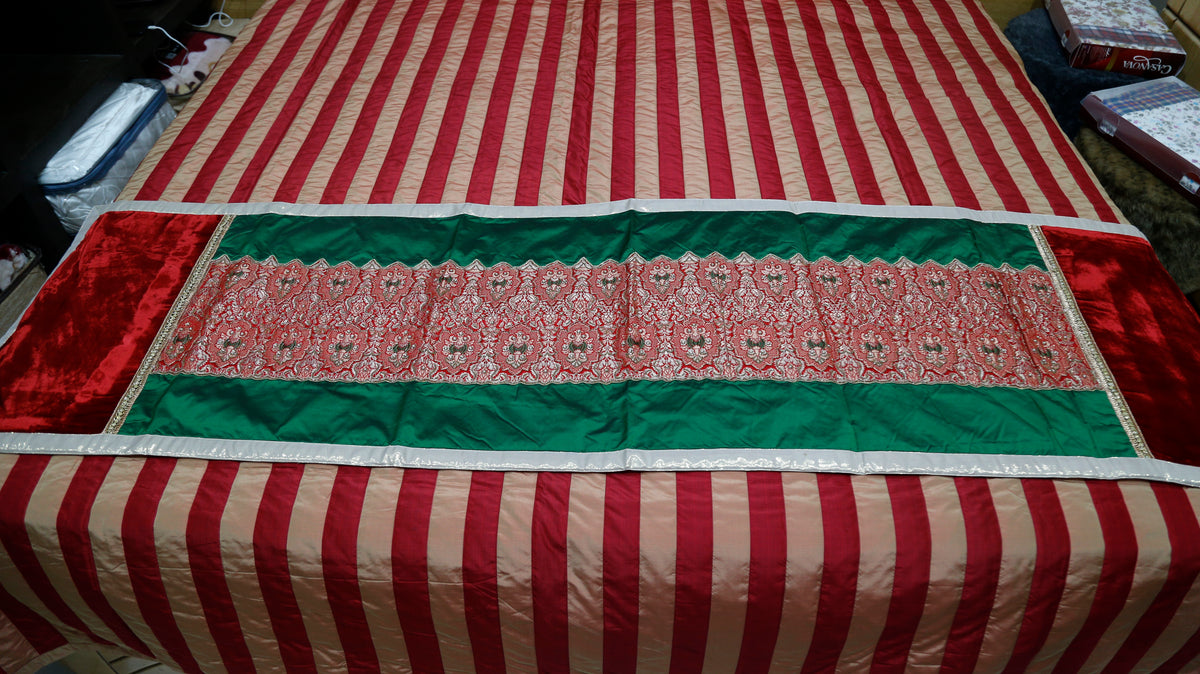 Close-up of the green and red brocade runner fabric with a cream lace-effect border