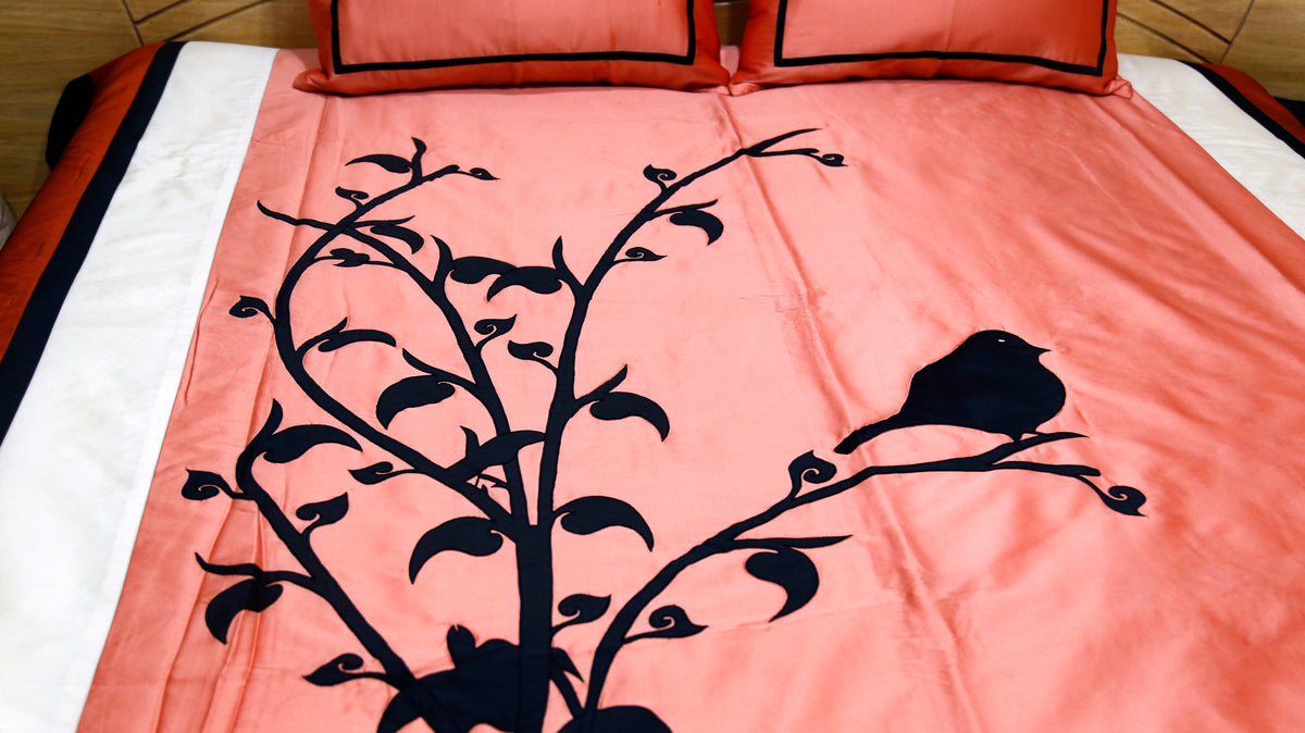 Close-up of black velvet bird and leafy branch applique on coral silk