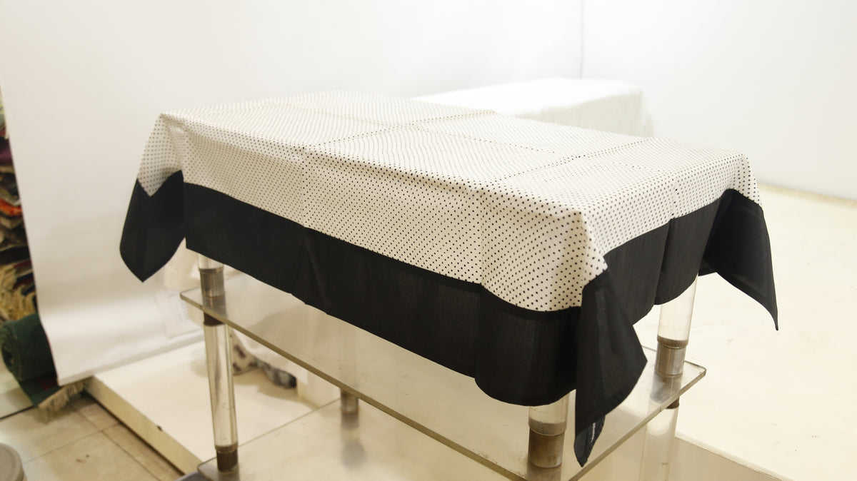 White sheer table cover with a scattered black polka-dot print, set over a solid black underskirt