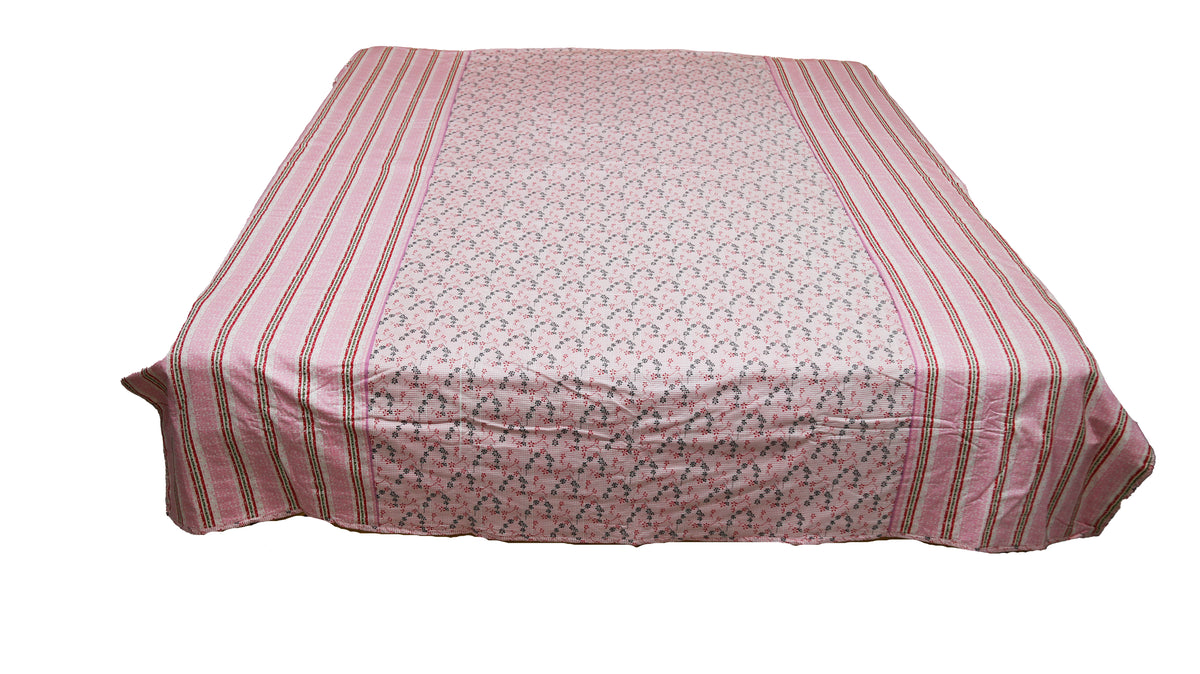 Dusty pink floral print dohar spread over a bed with striped pink and green borders