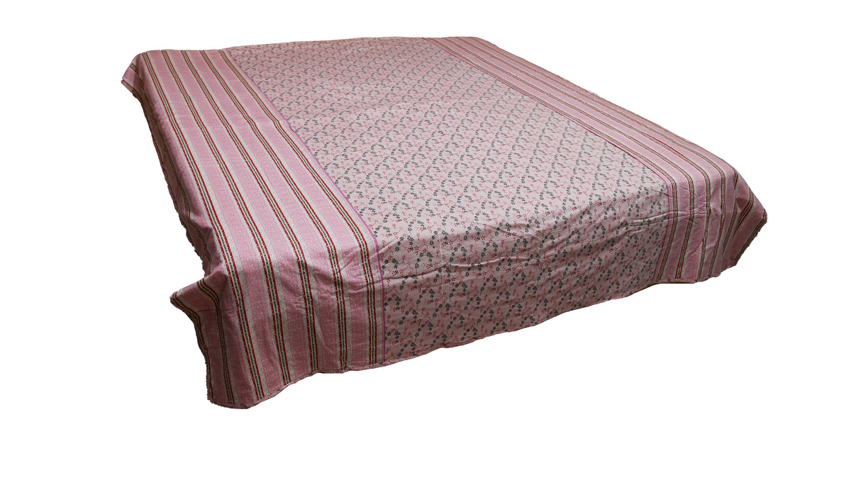 Dusty pink printed dohar on a bed, angled view showing the striped side border