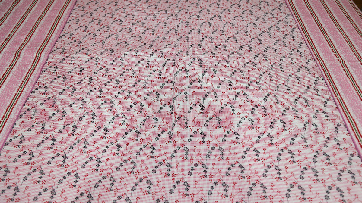 Close-up of small pink and green floral sprigs printed on the dusty pink dohar